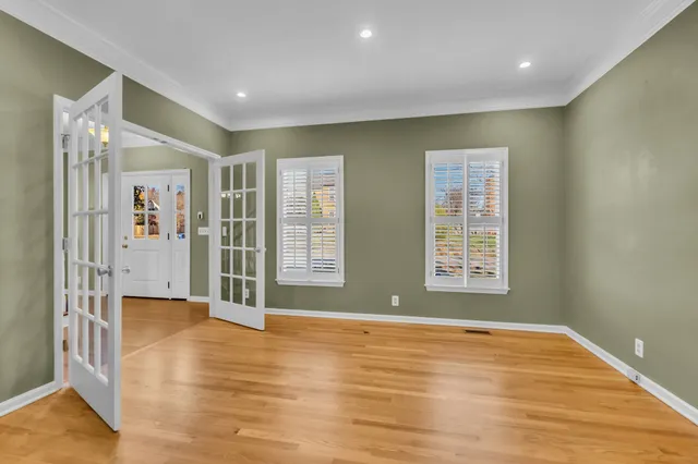 a view of an empty room with wooden floor and a window