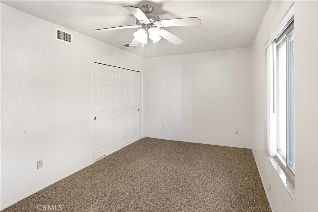 63542 Jadeite Street Joshua Tree, CA 92252 - Photo 21 of 37 an empty room with a window and a fan