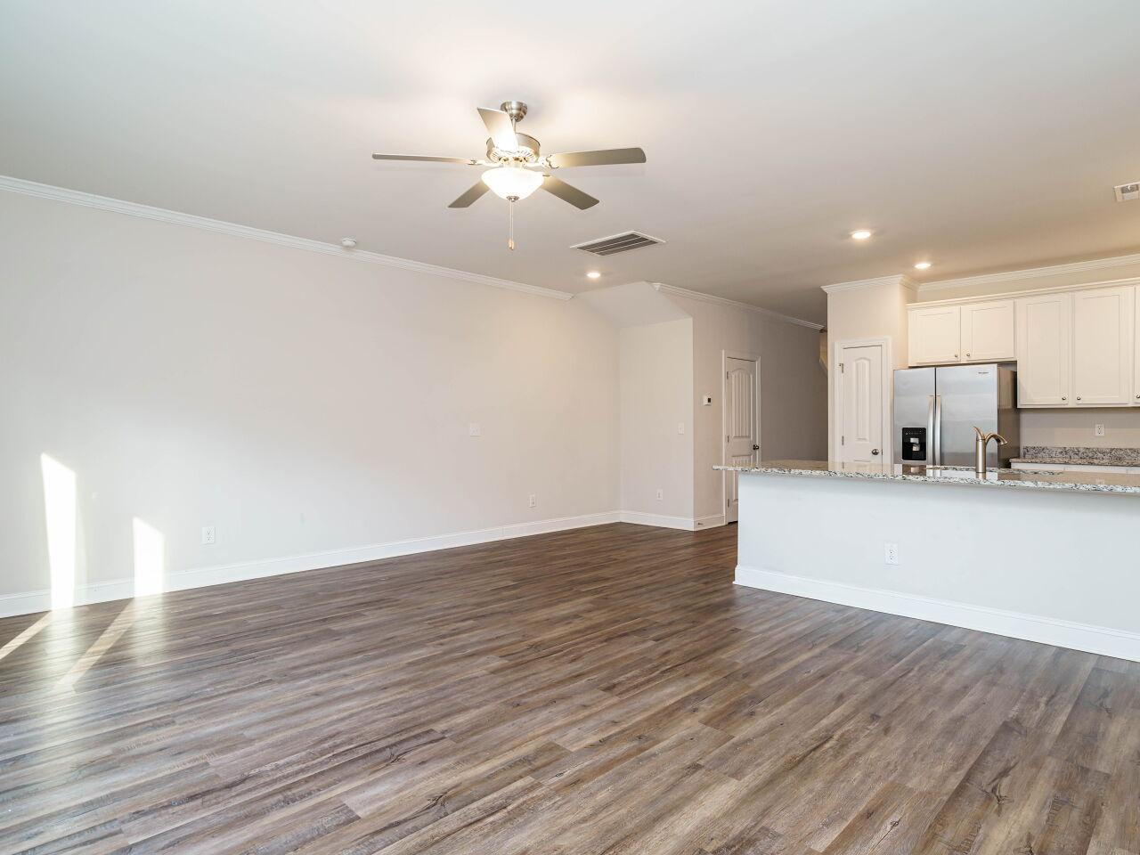 6914 Eddy Point Lane Raleigh, NC 27616 - Photo 9 of 33 a view of an empty room and kitchen with wooden floor