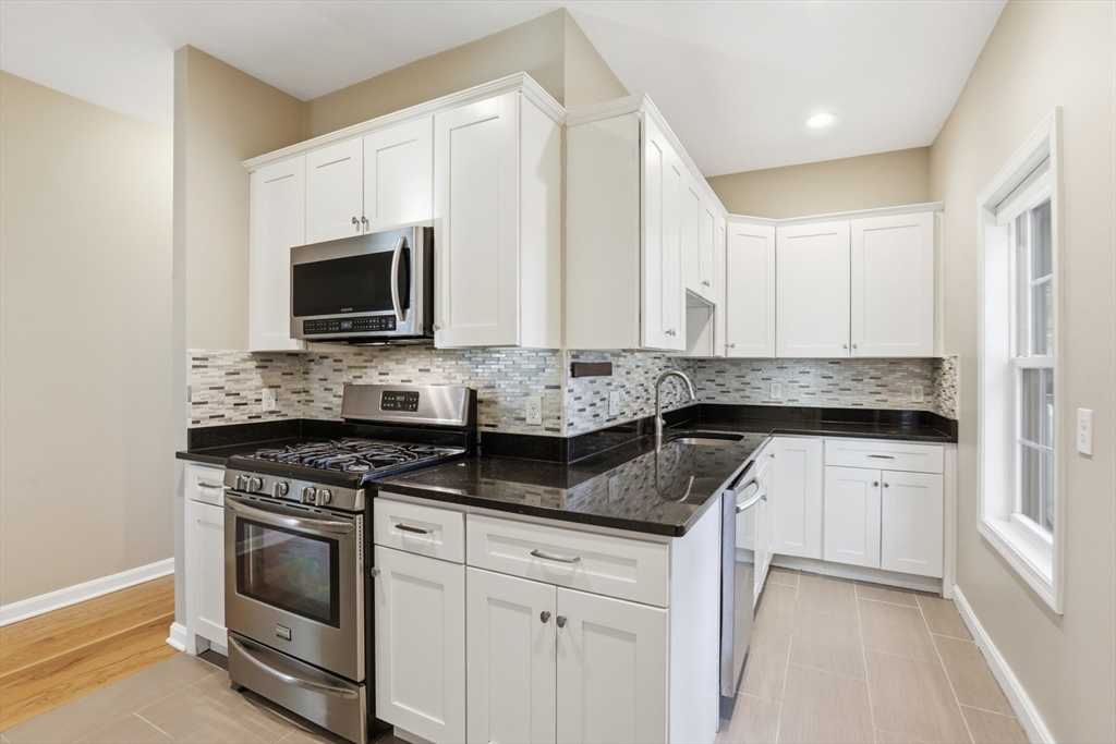 9 Montgomery Avenue, Unit 1 Somerville, MA 02145 - Photo 11 of 27 a kitchen with granite countertop white cabinets white stainless steel appliances and a sink