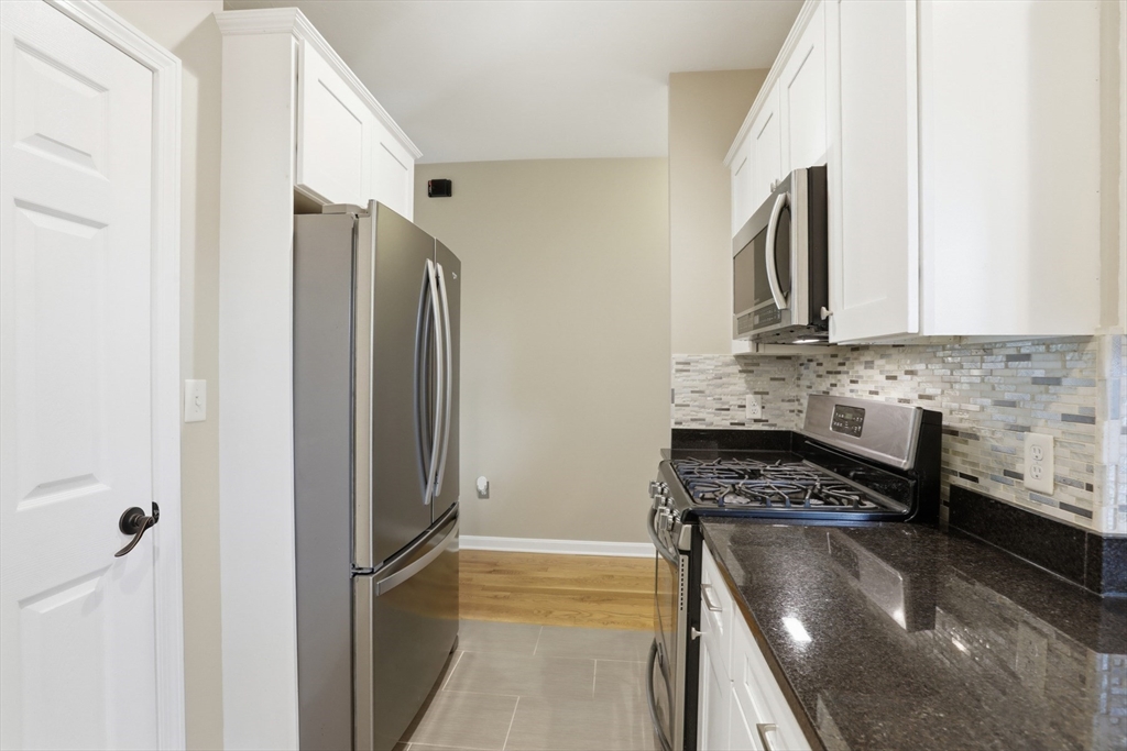 9 Montgomery Avenue, Unit 1 Somerville, MA 02145 - Photo 13 of 27 a kitchen with stainless steel appliances granite countertop a refrigerator a stove and a sink
