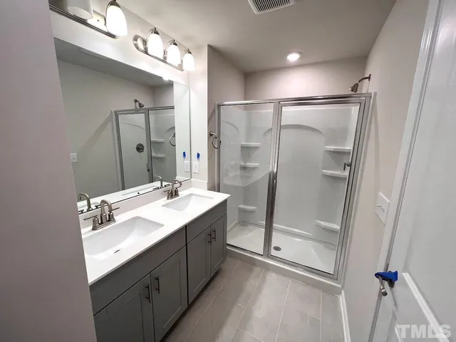 a bathroom with a double vanity sink mirror and shower