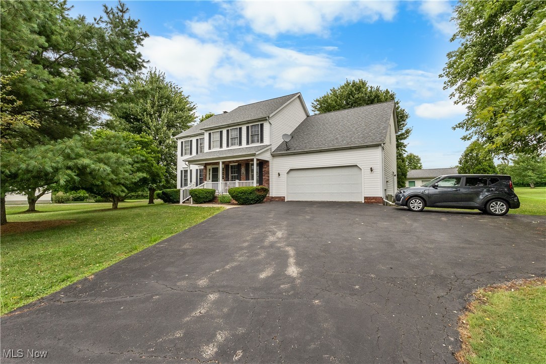 7665 Brakeman Road Painesville, OH 44077 - Photo 1 of 34 View of front of house with a porch, a garage, asphalt driveway, a front lawn, and a shingled roof