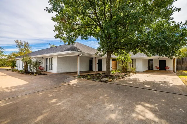 a view of a house with a yard and large tree