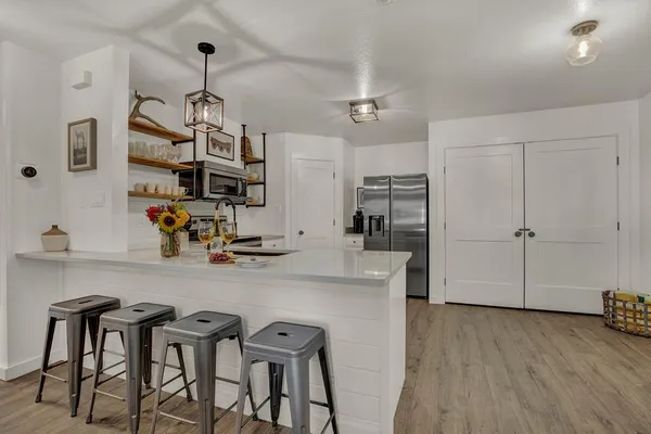 a kitchen with stainless steel appliances granite countertop a table chairs refrigerator and microwave