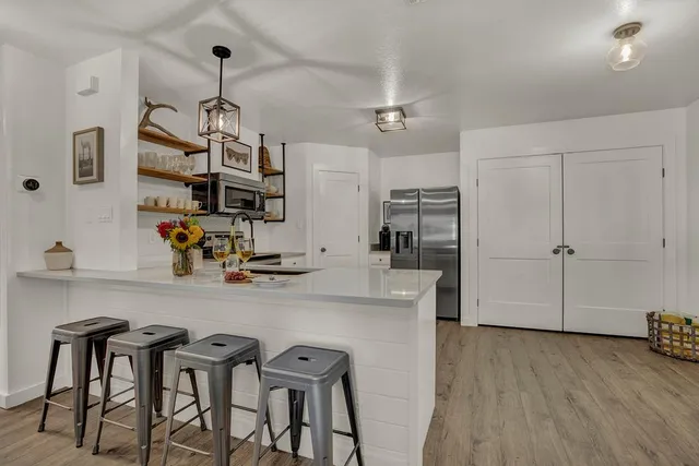 a kitchen with stainless steel appliances granite countertop a table chairs refrigerator and microwave