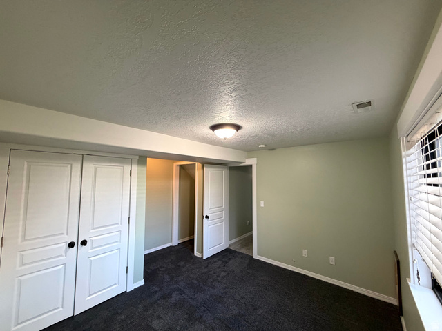 202 375 West Providence, UT 84332 - Photo 24 of 61 Unfurnished bedroom with a large closet and storage, dark carpet, and a plenty of light