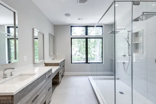 a bathroom with a granite countertop tub a double vanity sink a mirror and a shower