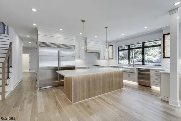 a large kitchen with kitchen island a large counter space a sink stainless steel appliances and cabinets