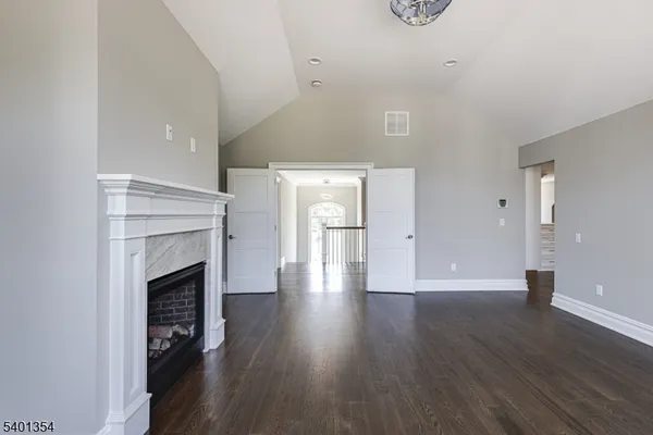 a view of an empty room with wooden floor and a fireplace