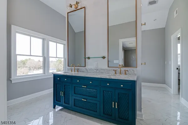 a bathroom with a granite countertop double vanity sink and mirror with window