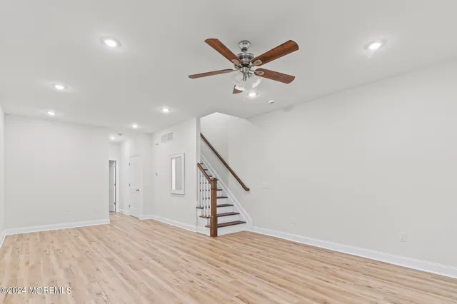 a view of an empty room with wooden floor and stairs