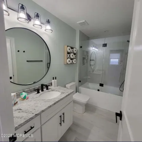a bathroom with a granite countertop sink mirror toilet and bathtub