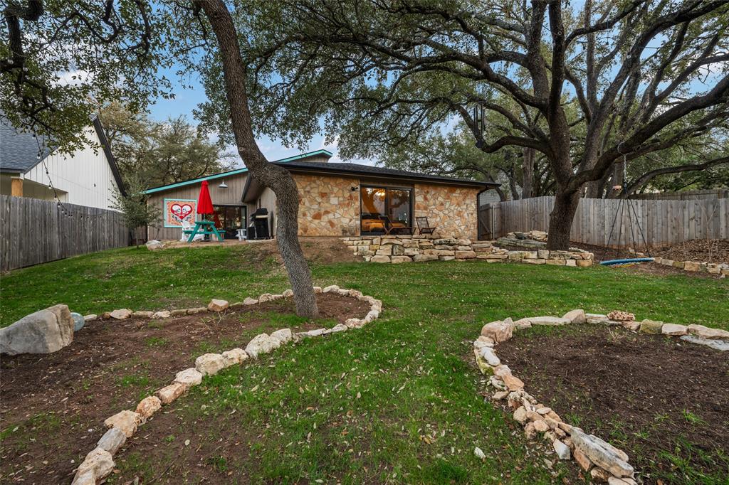 2210 Red Fox Road Austin, TX 78734 - Photo 20 of 40 Mature trees and terraced landscaping frame the rear facade of this unique residence.
