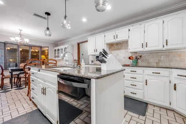 a kitchen with stainless steel appliances granite countertop a stove top oven a sink dishwasher a dining table and chairs with wooden floor