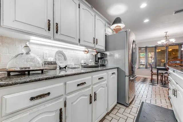 a kitchen with stainless steel appliances granite countertop a stove a sink dishwasher a dining table and chairs with wooden floor