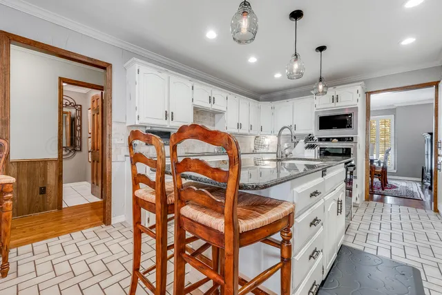 a kitchen with stainless steel appliances granite countertop a stove a refrigerator a kitchen island a dining table and chairs with wooden floor