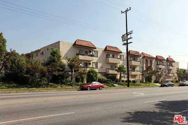 a city street with tall buildings and cars parked on the side of road