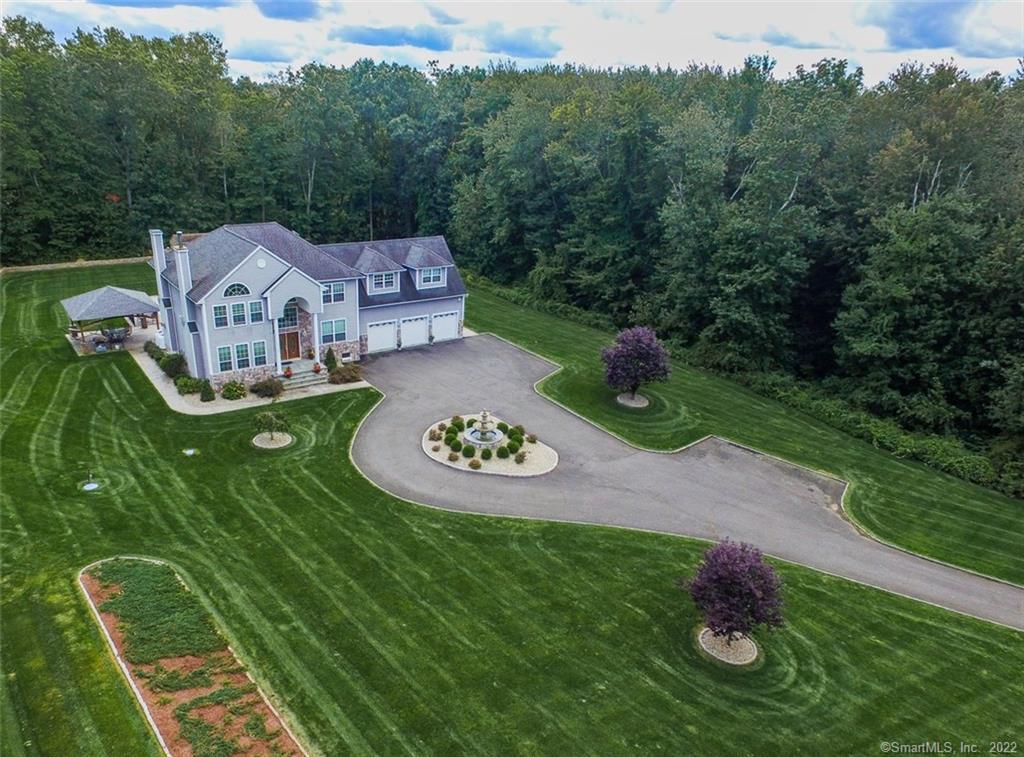 an aerial view of a house with pool big yard and large trees