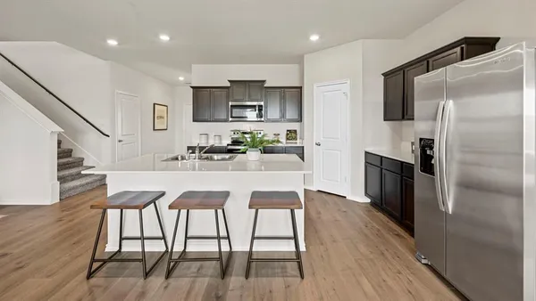 a kitchen with stainless steel appliances granite countertop a refrigerator a stove a sink a dining table and chairs with wooden floor