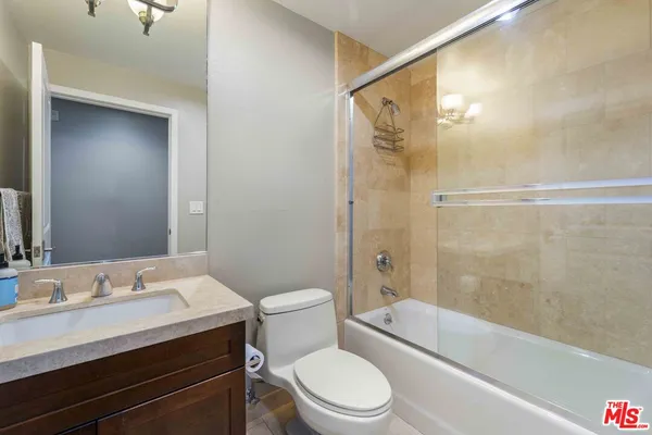 a bathroom with a granite countertop bathtub shower sink mirror vanity and toilet