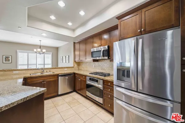 a kitchen with stainless steel appliances granite countertop a refrigerator a stove and a sink