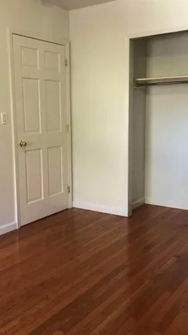 a view of an empty room with wooden floor and closet