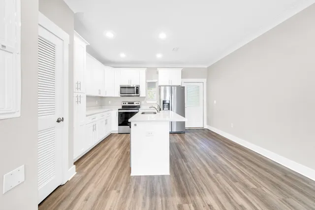 a view of a kitchen with wooden floor and electronic appliances