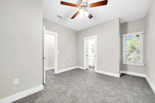 an empty room with windows and fan