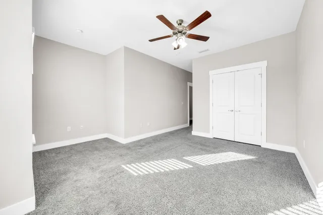 an empty room with a ceiling fan and window
