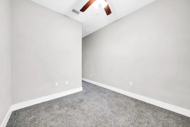 an empty room with ceiling fan and window