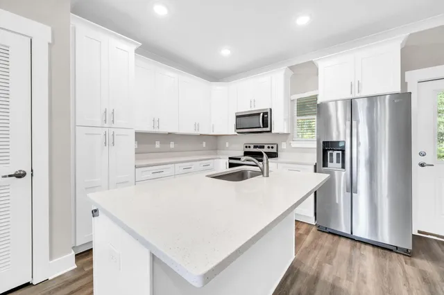 a kitchen with a refrigerator a stove top oven a sink and cabinets with wooden floor