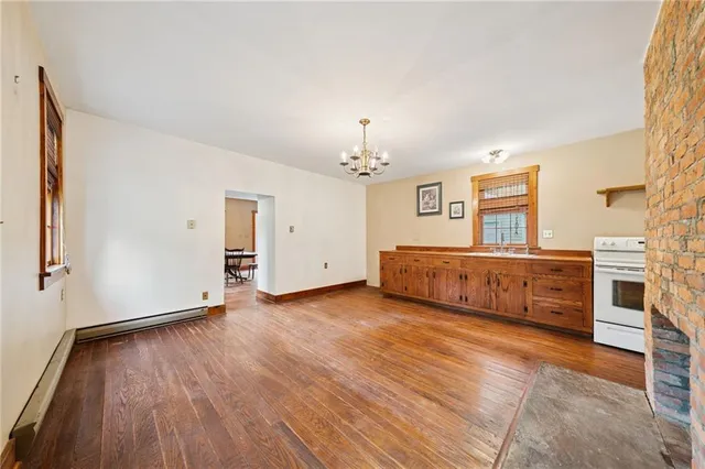 an empty room with wooden floor chandelier and windows