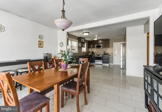 a dining room with stainless steel appliances kitchen island granite countertop a table chairs and a refrigerator