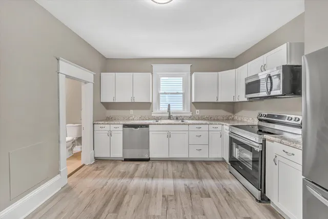 a kitchen with a white cabinets and wooden floor