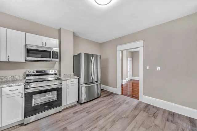 a kitchen with granite countertop a refrigerator and a stove top oven