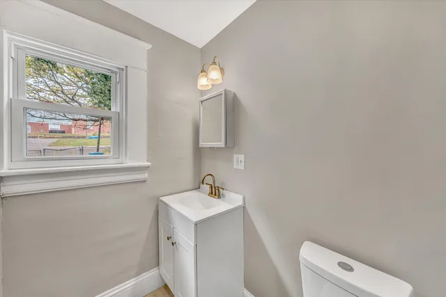 a bathroom with a toilet a sink a window and mirror