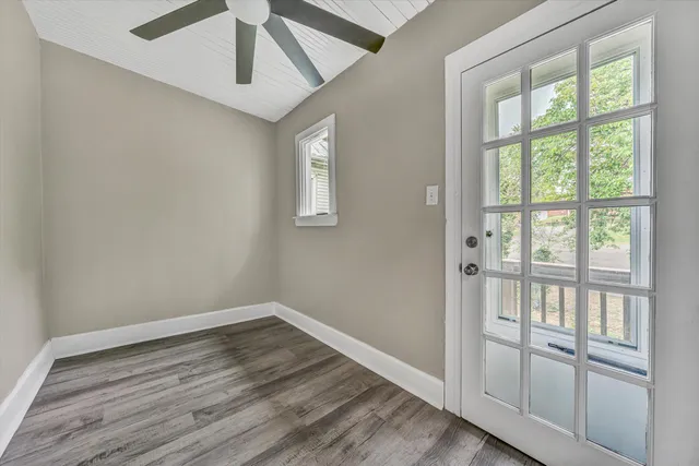 an empty room with wooden floor fan and windows