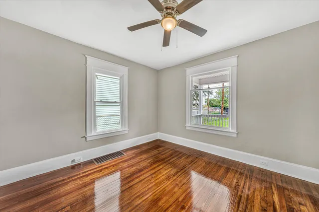 a view of an empty room with a window and wooden floor