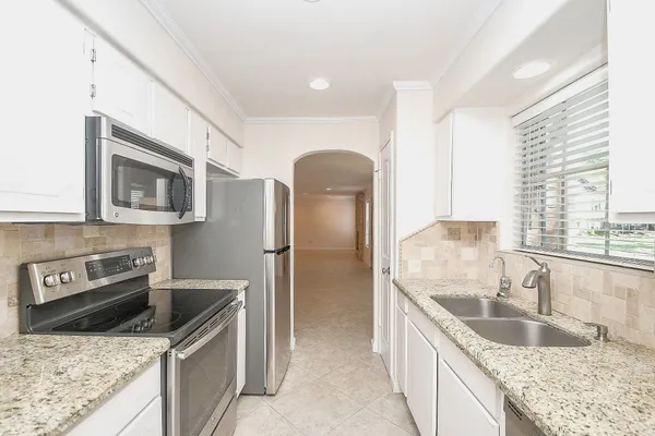 a large kitchen with granite countertop a sink and cabinets