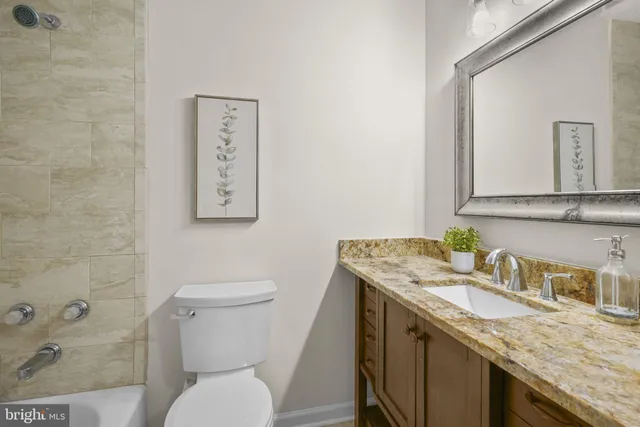 a bathroom with a granite countertop toilet sink and mirror