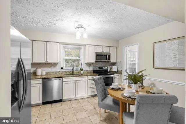 a kitchen with stainless steel appliances granite countertop a stove top oven a sink dishwasher a dining table and chairs with wooden floor