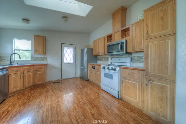 a kitchen with stainless steel appliances granite countertop a sink a stove a refrigerator cabinets and wooden floor