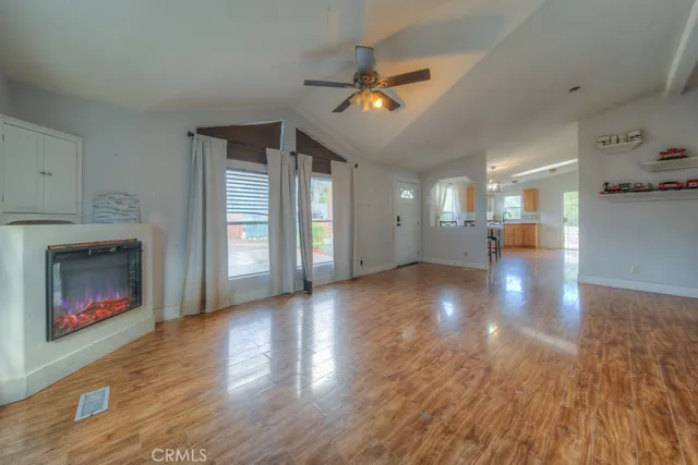 a view of an empty room with wooden floor and a fireplace