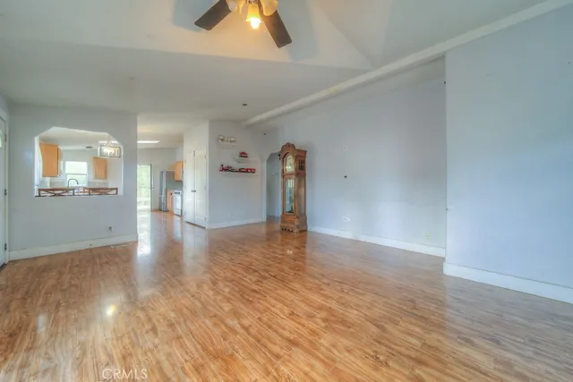 a view of a livingroom with wooden floor and a kitchen space