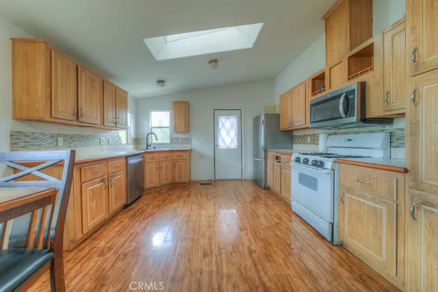 a kitchen with stainless steel appliances granite countertop wooden cabinets a stove a sink and a wooden floors
