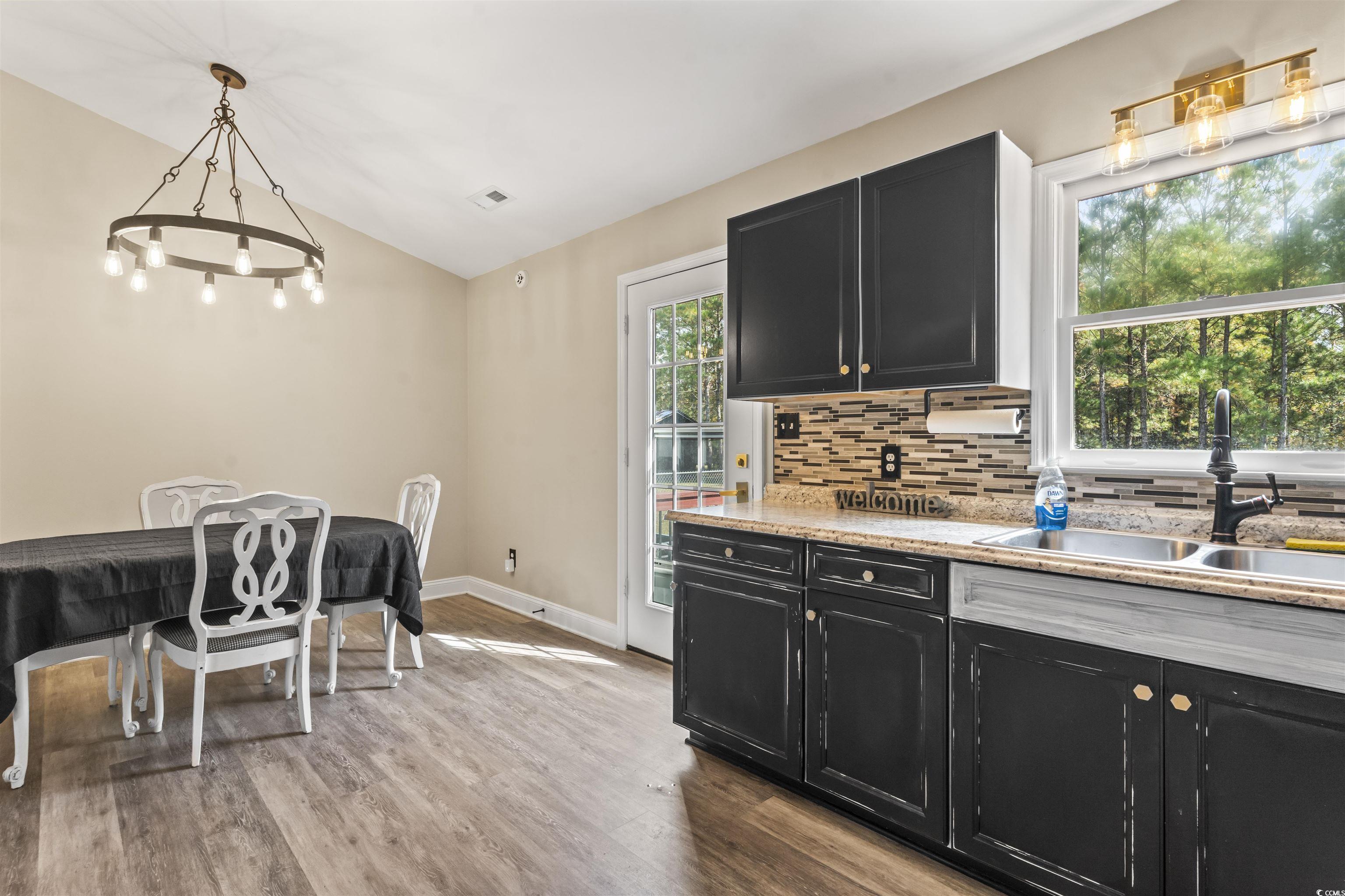 1495 Wilderness Lane Loris, SC 29569 - Photo 6 of 37 Kitchen featuring dark cabinetry, light wood-style flooring, tasteful backsplash, pendant lighting, and lofted ceiling