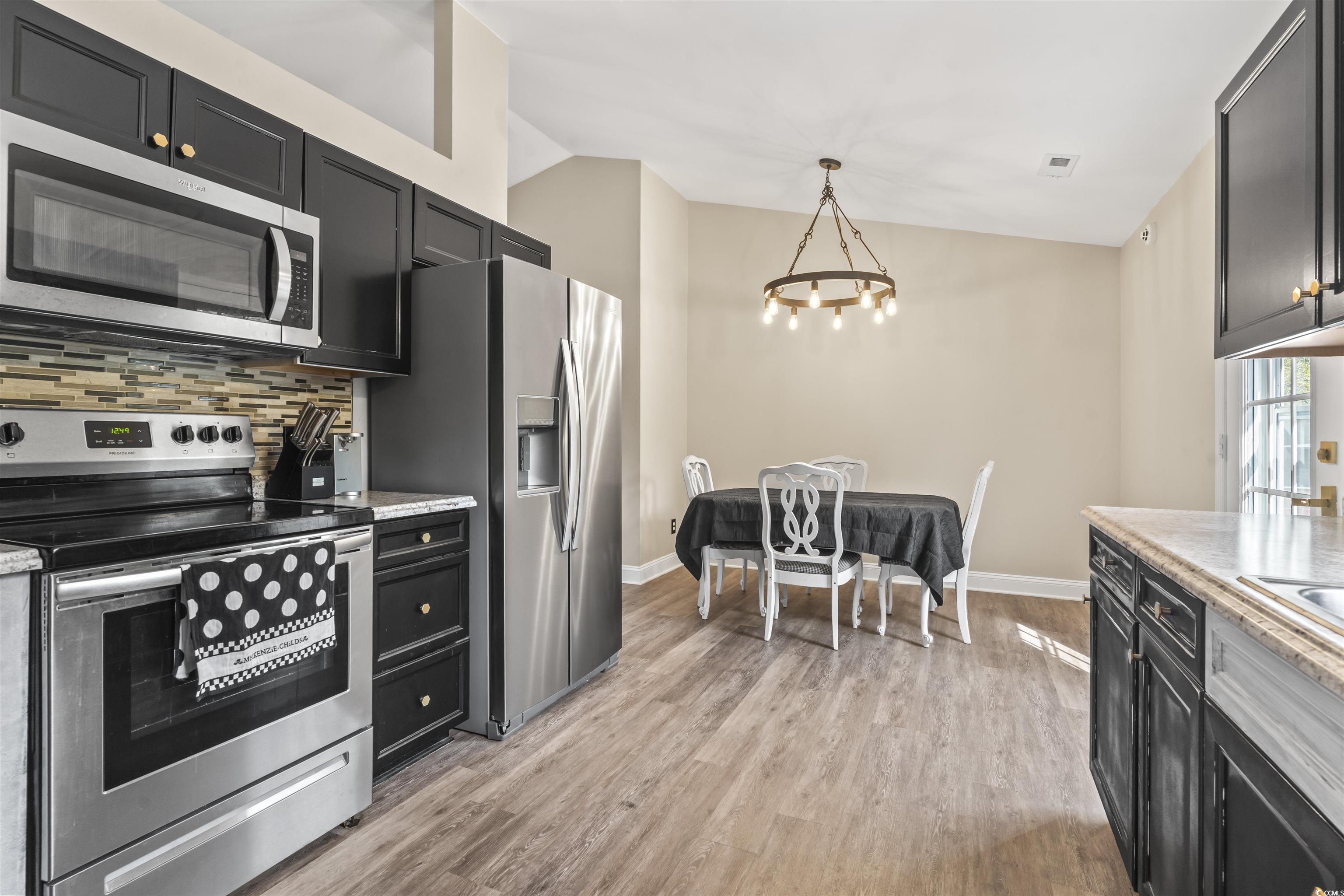 1495 Wilderness Lane Loris, SC 29569 - Photo 9 of 37 Kitchen with stainless steel appliances, dark cabinets, lofted ceiling, backsplash, and pendant lighting