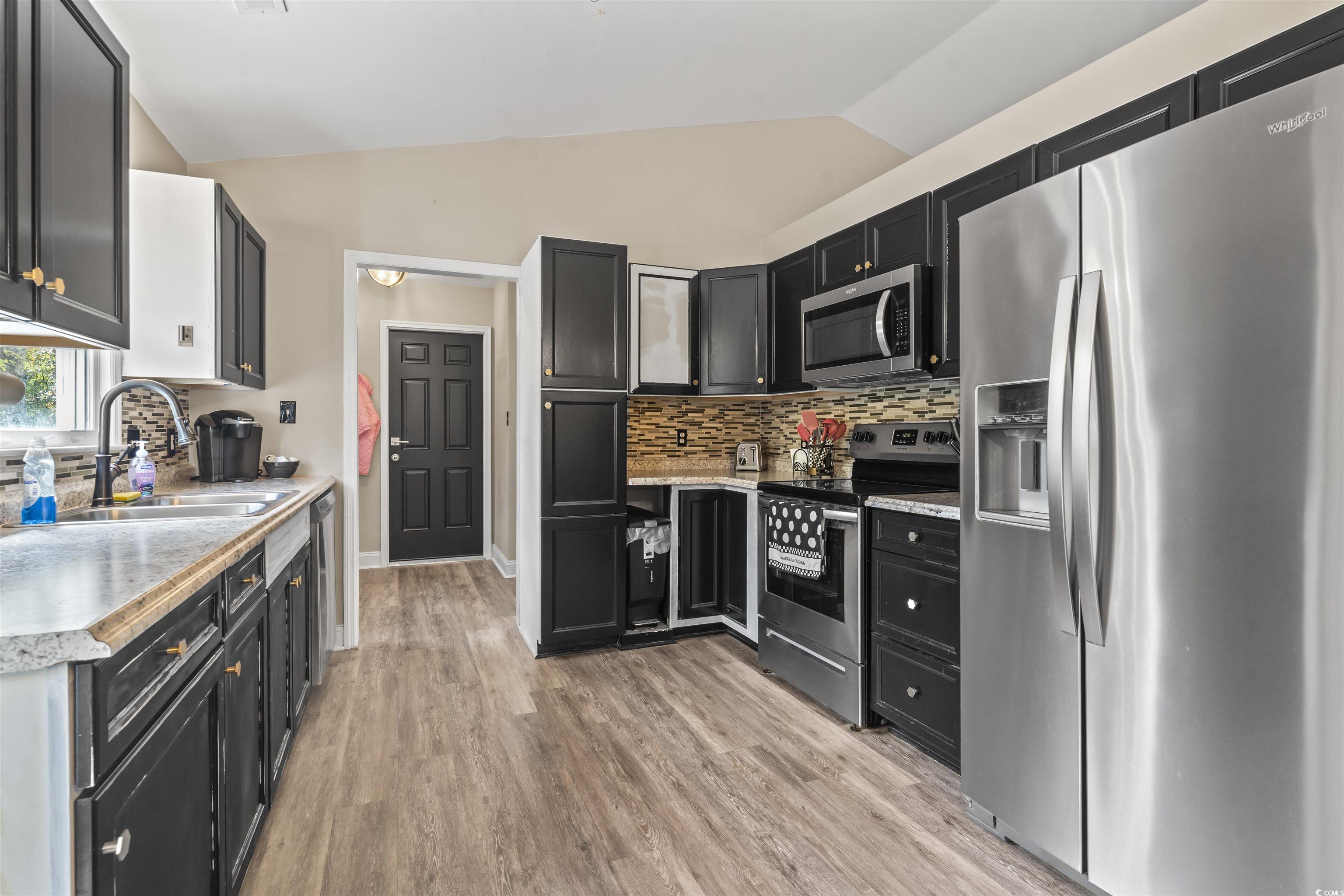 1495 Wilderness Lane Loris, SC 29569 - Photo 10 of 37 Kitchen with dark cabinetry, stainless steel appliances, tasteful backsplash, vaulted ceiling, and light wood finished floors