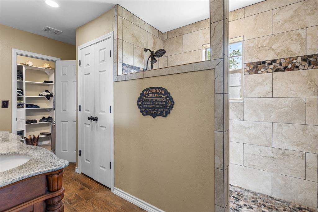 13315 Highway 281 Scotland, TX 76379 - Photo 19 of 40 Walk-in shower featuring light-toned large format tile, pebble stone accent strip, and a pebble stone floor